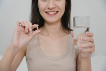 Woman holding a red and blue capsule pill in hand, preparing to take medicine for health care or treatment. Ideal for medical, pharmaceutical, or wellness-related content and campaigns.