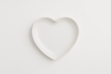 Obraz premium Glossy ceramic plate shaped like a heart positioned centrally on a white backdrop. Minimalistic design with ample copy space. Symbolizes love and romance for special occasions.