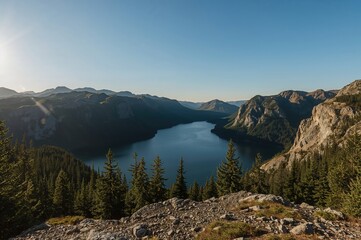 Scenic alpine lake at 1030 meters with evening sunlight reflecting on water and surrounding forest