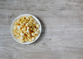 Top view of popcorn on empty wooden background, for copy space. Concept of eating, snacking, relaxing, watching movies.