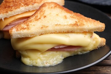 Delicious sandwiches with melted cheese and ham on wooden table, closeup
