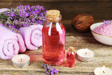 Lavender essential oil, flowers, candles, sea salt and towels on wooden table