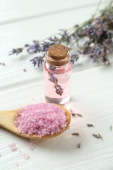 Lavender essential oil, flowers and sea salt on white wooden table, closeup