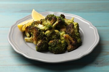 Tasty fried broccoli and lemon on light blue wooden table, closeup