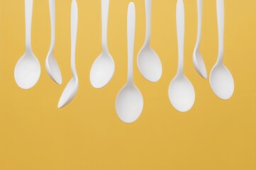 Floating white spoons on a bright yellow background