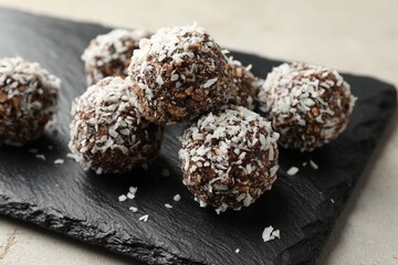 Tasty chocolate candies with nuts and coconut flakes on light table, closeup