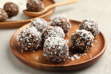 Tasty chocolate candies with nuts and coconut flakes on light table, closeup