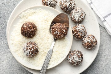 Making tasty chocolate candies with coconut flakes at grey table, top view