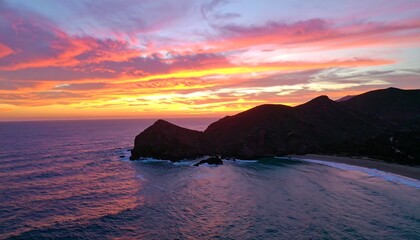 Vibrant sunset over ocean cove, dramatic clouds