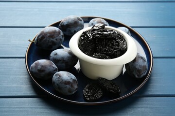 Dried prunes and fresh plums on blue wooden table, closeup