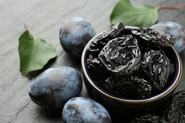 Dried prunes and fresh plums on black table, closeup