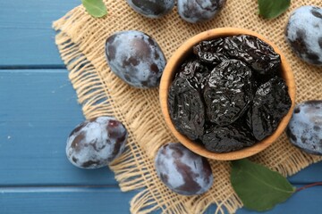 Dried prunes and fresh plums on blue wooden table, flat lay