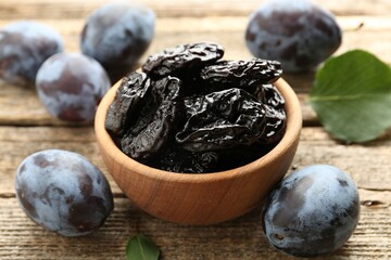 Dried prunes and fresh plums on wooden table, closeup