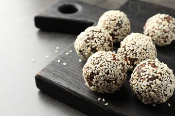 Tasty chocolate candies with nuts and sesame seeds on grey table, closeup