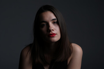 Fototapeta premium Mysterious Woman, Red Lips, Dramatic Low-Key Portrait, Studio Shot, Intense Gaze, Fashion Beauty.