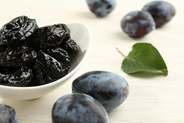 Dried prunes and fresh plums on wooden table, closeup