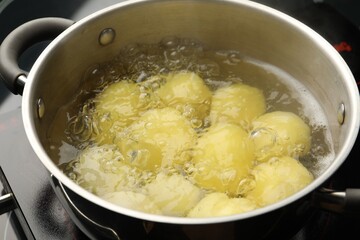 Young potatoes boiling in pot on stove, closeup