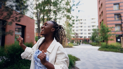 Fototapeta premium Young woman resting and relaxing while walking on city street in new eco-friendly residential complex. Relaxation and stress-free concept.