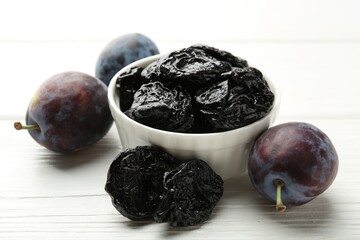 Dried prunes and fresh plums on white wooden table, closeup