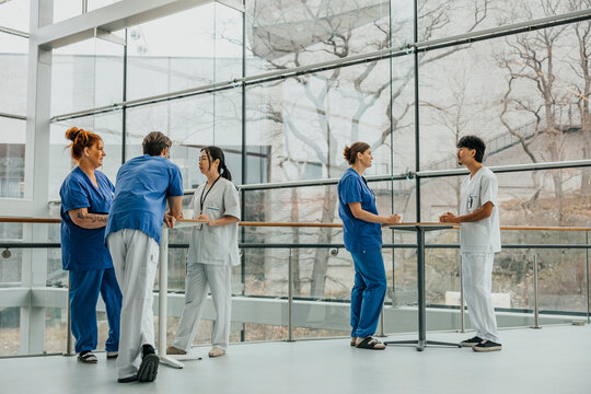 Male and female medical professionals discussing with each other during break time while standing in corridor of hospita