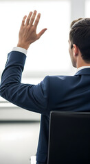 Businessman raising hand during corporate meeting in modern office, showing participation and engagement in a professional setting.