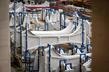 Munich Freiham - White Concrete Construction Elements Arranged In Industrial Site With Blue Metal Supports: Structural Components Prepared For Urban Infrastructure Development