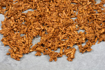 A pile of marinated grated smoked tofu is on a baking paper, ready for baking