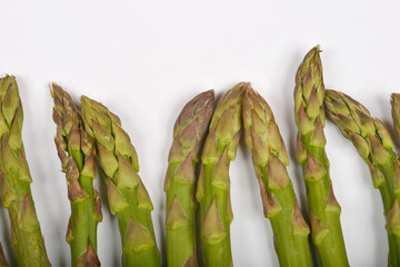 A close-up shows the tips of several fresh green asparagus spears against a plain white background