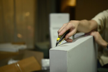 Close-Up of Hand Using Cutter Knife to Open Cardboard Box