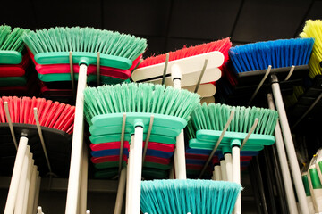 a collection of colorful brooms, displayed on a retail wall display for residential or commercial use.