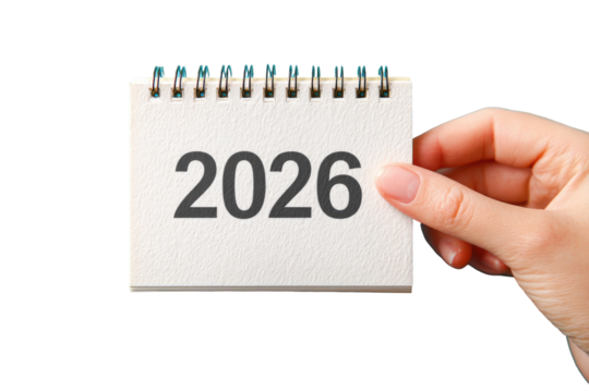 A hand holds a small calendar page displaying the year 2026