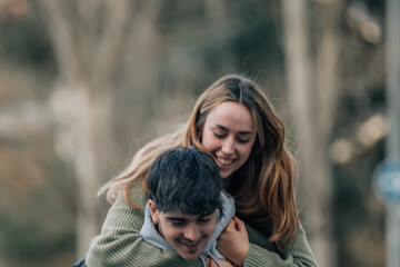 Fototapeta premium boy carrying girl on his back having fun, young couple