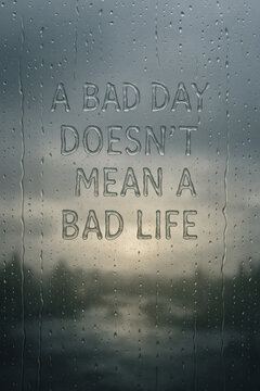 Motivational message on a rainy window: "A bad day doesn't mean a bad life.". Focuses on hope and resilience in difficult times.