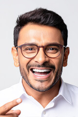 Obraz premium A smiling man wearing glasses gestures with his finger, exuding confidence and approachability against a plain background.