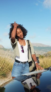 Woman checks a map on car hood before starting her hike in Sierra de Tramuntana, Majorca. Concept of lifestyle, exploration, planning.