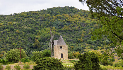Naklejka premium Old, historic windmill in Grimaud with the Massif des Maures mountains in France in spring, Cote d'Azur, French Riviera