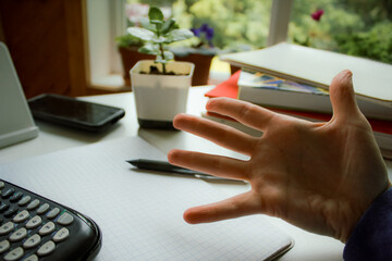 a study environment with a person reaching out a hand, expressing concern or confusion. a calculator and graph paper is in view. education background