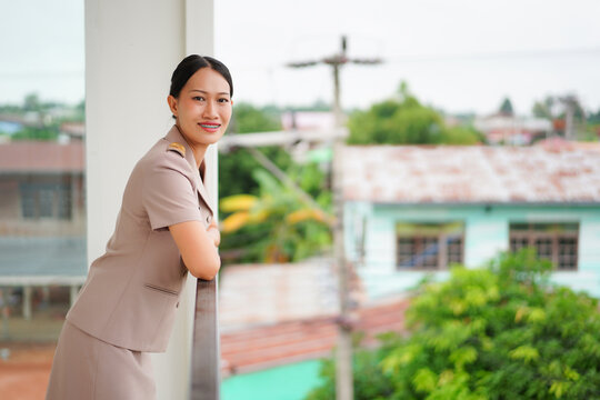 Professional woman in elegant attire posing at a balcony with greenery and urban backdrop, showcasing confidence and modern lifestyle in a vibrant setting - Powered by Adobe