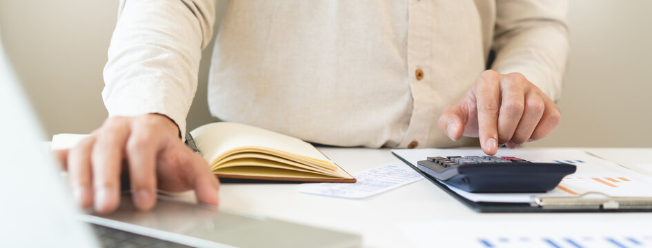 Deduction planning, debt asian accountant hand using calculator to calculating money balance from bill and income, cost budget expenses for pay money form personal individual on table at home.