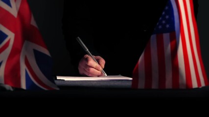 Hand signing a trade deal with American USA flag and British Union Jack - Powered by Adobe