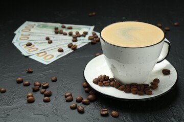 Cup of aromatic coffee, dollar banknotes and roasted beans on dark textured table, closeup
