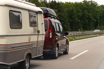 Caravan travels along a highway surrounded by greenery on a sunny day