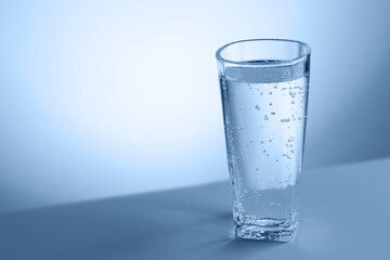 Refreshing soda water in glass on table against light blue gradient background, closeup. Space for text