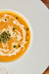 Indulge in a Deliciously Creamy Pumpkin Soup Accentuated with Seeds and a Flavorful Drizzle