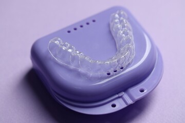 One clear aligner and retainer case on violet background, closeup