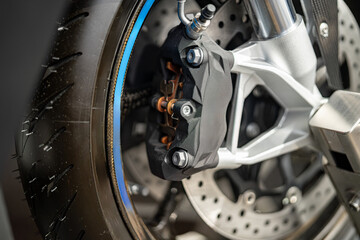 High-performance motorcycle brake caliper showcased on a racing tire in a workshop setting during...
