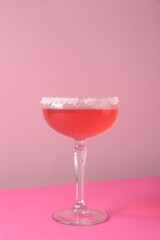 Martini cocktail with sugar in glass on pink background, closeup