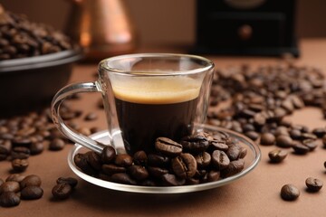 Cup of hot coffee and beans on brown background, closeup