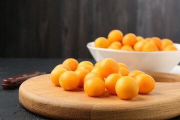 Ripe yellow cherry plums, wooden board and knife on black table, closeup