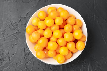 Ripe yellow cherry plums on black table, top view